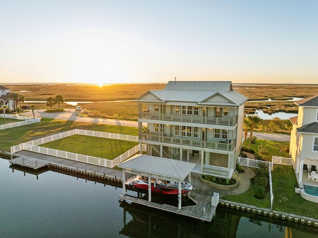 back house at dusk with a balcony and a water view