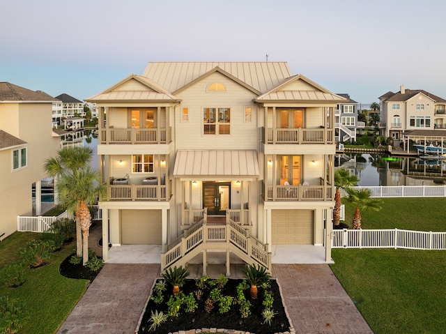 multi unit property featuring covered porch, a balcony, a garage, and a lawn