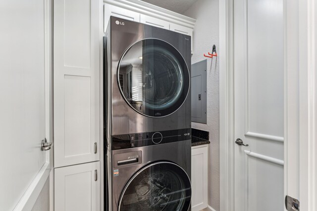 laundry room with cabinets, stacked washer / dryer, and electric panel