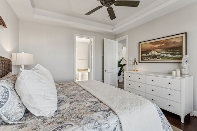 bedroom with connected bathroom, dark hardwood / wood-style floors, a raised ceiling, and ceiling fan