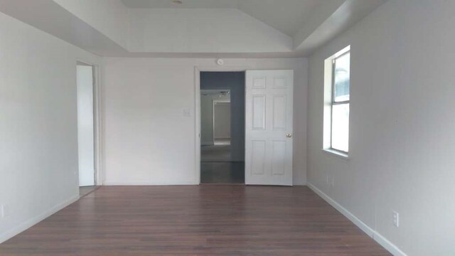 empty room with lofted ceiling and dark wood-type flooring