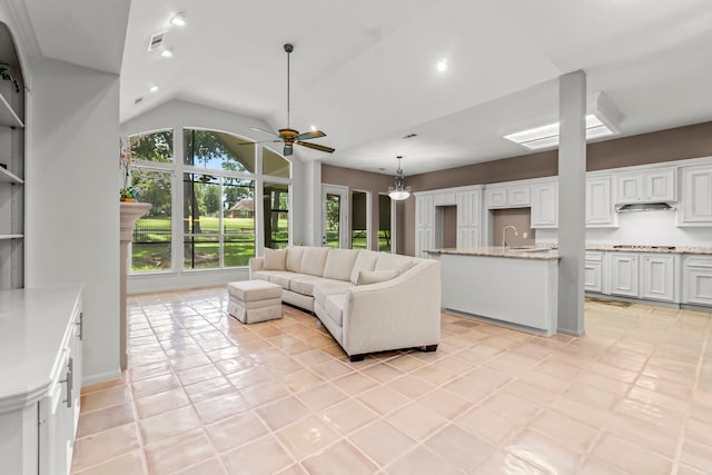 tiled living room with lofted ceiling, sink, and ceiling fan with notable chandelier