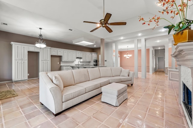 living room with light tile patterned floors, ceiling fan with notable chandelier, lofted ceiling, and sink