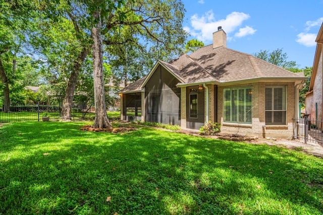 rear view of house with a lawn and a sunroom