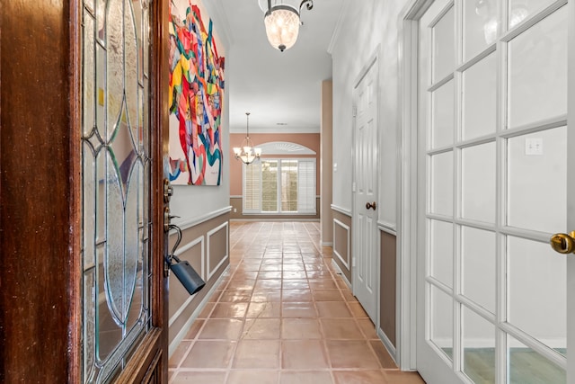 hallway featuring light tile patterned floors, crown molding, and a notable chandelier