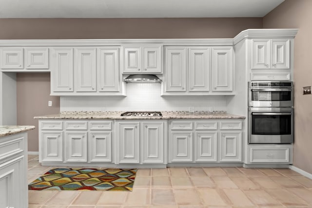 kitchen featuring backsplash, white cabinetry, light stone countertops, and stainless steel appliances