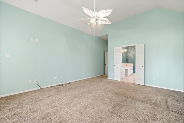 unfurnished bedroom featuring connected bathroom, light colored carpet, high vaulted ceiling, and ceiling fan