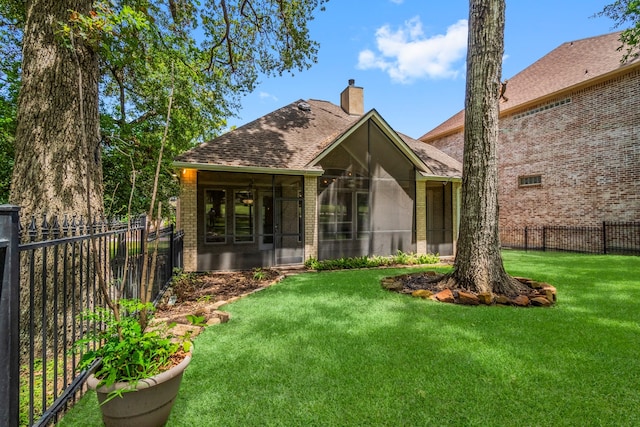 rear view of house featuring a sunroom and a lawn