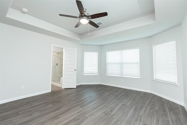 interior space with a tray ceiling, ceiling fan, and dark wood-type flooring