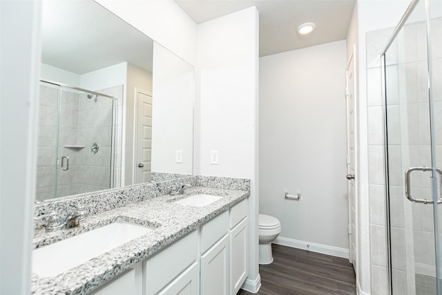 bathroom featuring walk in shower, hardwood / wood-style flooring, vanity, and toilet