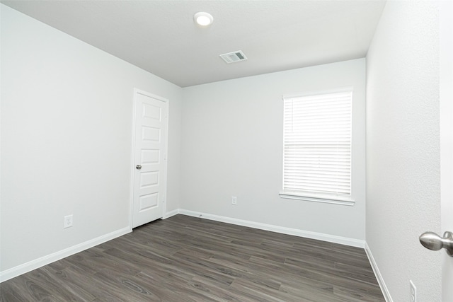 spare room with a wealth of natural light and dark hardwood / wood-style flooring