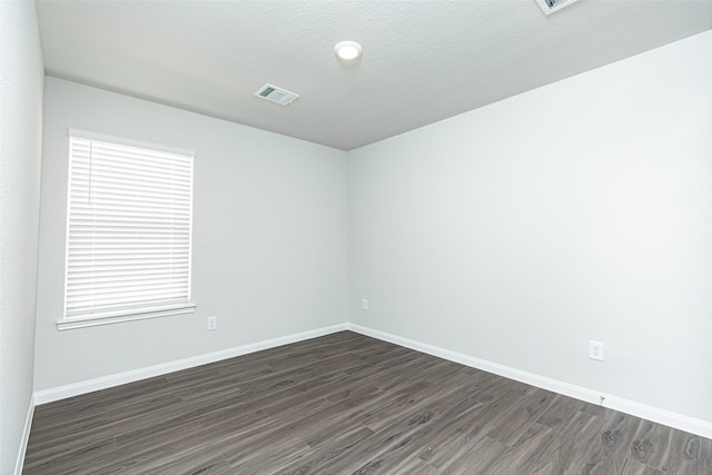 spare room featuring a textured ceiling, dark wood-type flooring, and a wealth of natural light