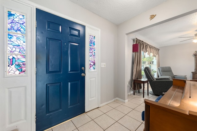 tiled foyer entrance with a textured ceiling and ceiling fan