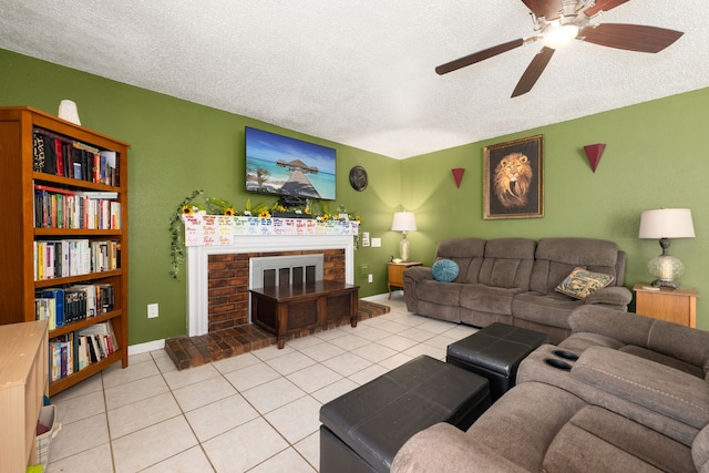 living room with ceiling fan, light tile patterned floors, a textured ceiling, and a brick fireplace