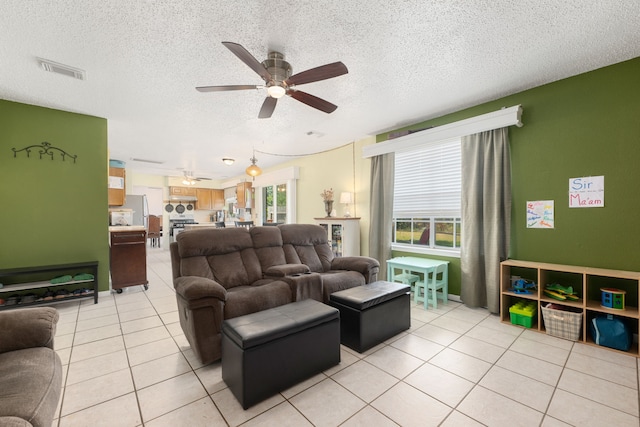 living room with a textured ceiling, ceiling fan, and light tile patterned flooring