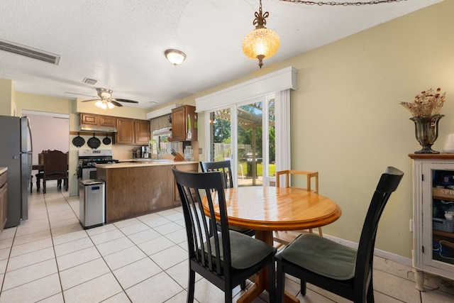 dining room with ceiling fan, light tile patterned flooring, and a textured ceiling