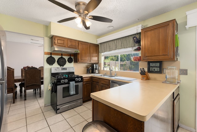 kitchen with kitchen peninsula, appliances with stainless steel finishes, a textured ceiling, sink, and light tile patterned floors