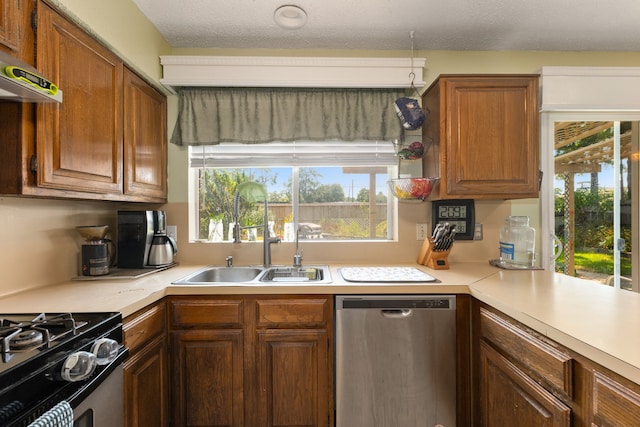 kitchen with appliances with stainless steel finishes, a textured ceiling, a healthy amount of sunlight, and sink