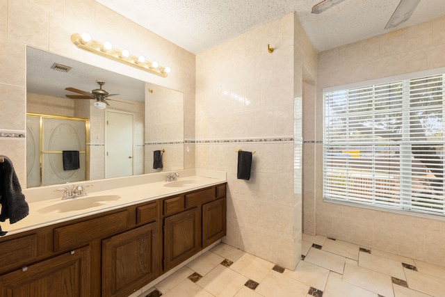 bathroom featuring a textured ceiling, plenty of natural light, and tile walls