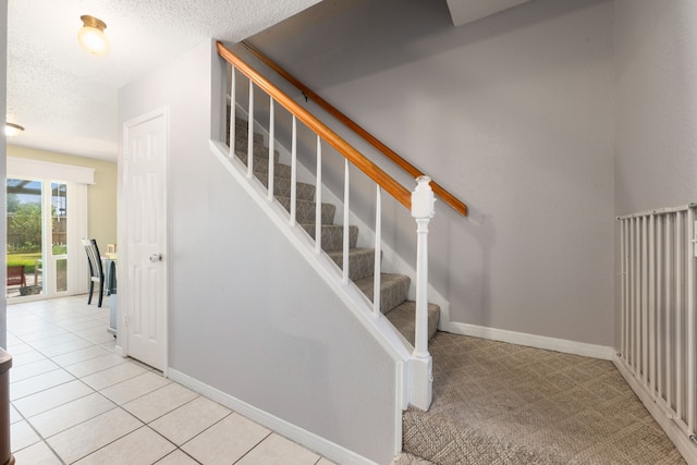 staircase featuring tile patterned flooring and a textured ceiling