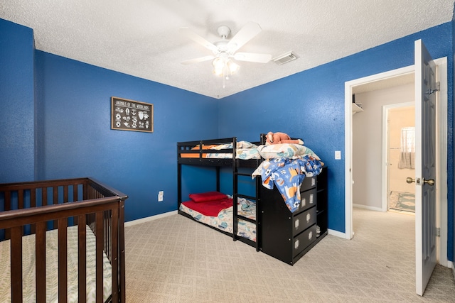 bedroom with ceiling fan, light carpet, and a textured ceiling