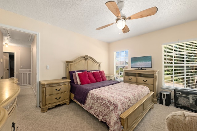 bedroom featuring ceiling fan, light colored carpet, and a textured ceiling