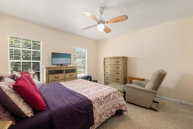 carpeted bedroom with ceiling fan and a textured ceiling