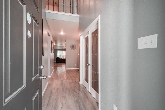 hall with light hardwood / wood-style flooring and french doors