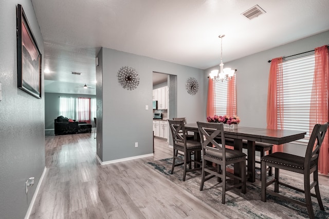 dining room featuring ceiling fan with notable chandelier and light wood-type flooring