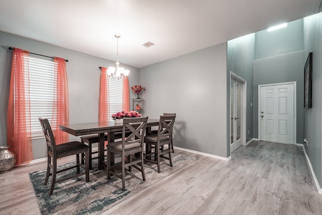 dining area featuring light wood-type flooring, plenty of natural light, and a notable chandelier