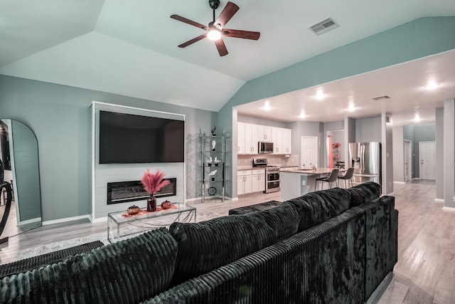 living room featuring light hardwood / wood-style floors, vaulted ceiling, ceiling fan, and sink