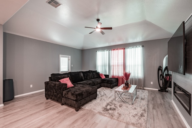 living room with a wealth of natural light, ceiling fan, light hardwood / wood-style floors, and vaulted ceiling