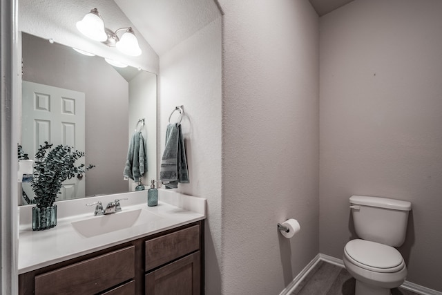 bathroom with hardwood / wood-style floors, vanity, toilet, and vaulted ceiling