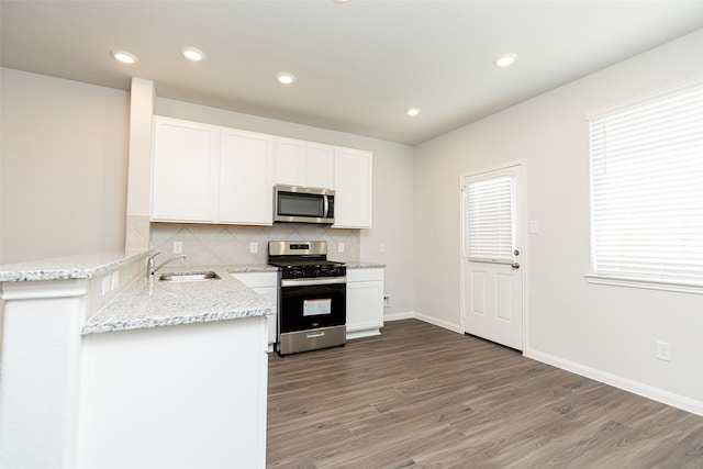 kitchen with sink, stainless steel appliances, backsplash, kitchen peninsula, and white cabinets