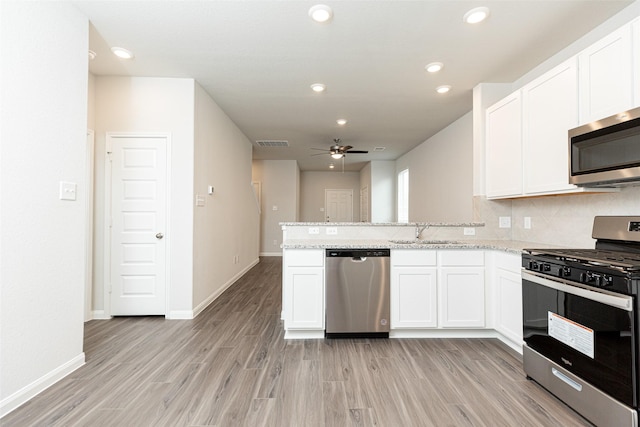 kitchen with kitchen peninsula, stainless steel appliances, and white cabinetry