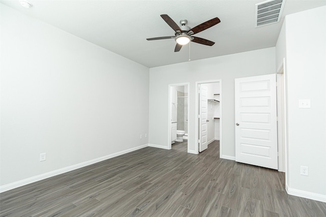 unfurnished bedroom featuring ensuite bath, ceiling fan, dark hardwood / wood-style floors, a walk in closet, and a closet