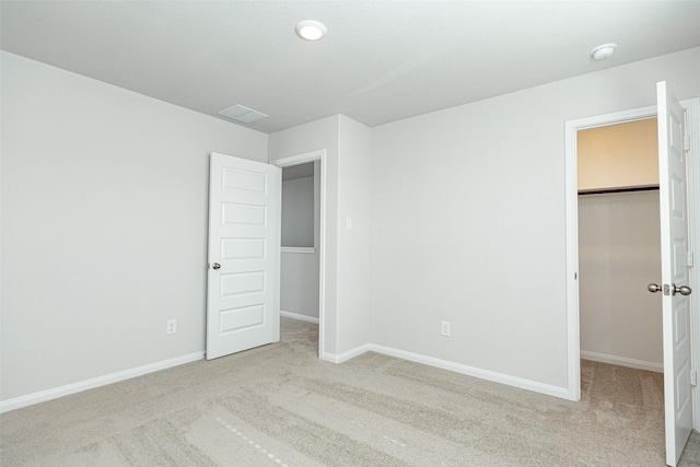 unfurnished bedroom featuring light colored carpet, a spacious closet, and a closet