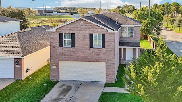 view of front of house featuring a front lawn, brick siding, driveway, and an attached garage