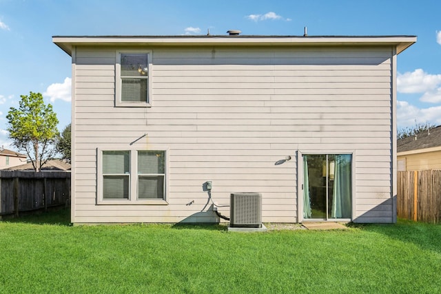 back of property with cooling unit, a fenced backyard, and a lawn