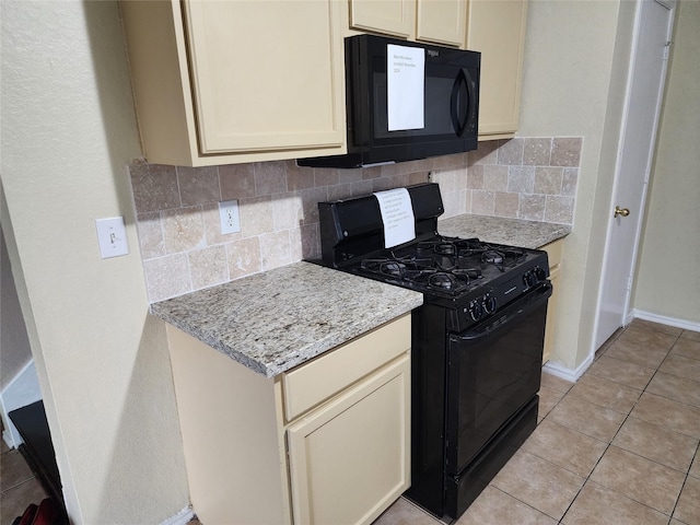 kitchen with tasteful backsplash, cream cabinetry, black appliances, and light tile patterned floors