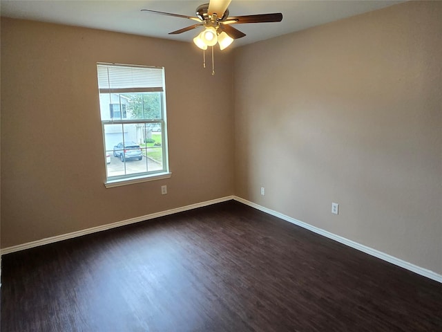 empty room featuring baseboards, dark wood finished floors, and a ceiling fan