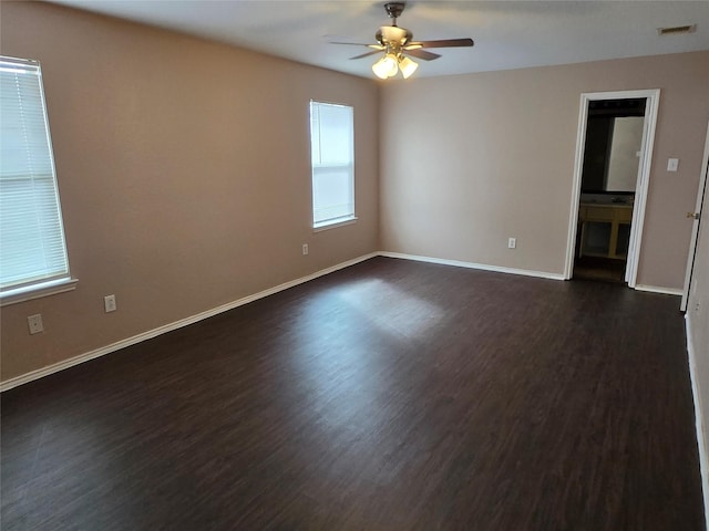 empty room featuring baseboards, visible vents, ceiling fan, and dark wood-type flooring