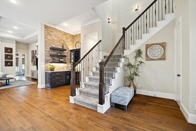 staircase with hardwood / wood-style flooring, a towering ceiling, and ornamental molding