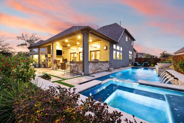 view of pool with a patio area, a bar, and an in ground hot tub