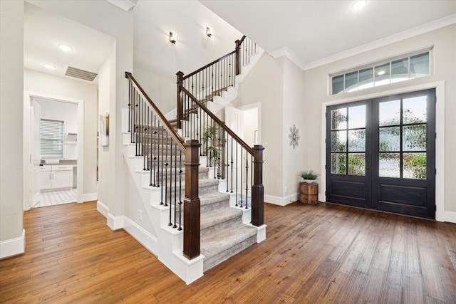 foyer entrance featuring hardwood / wood-style flooring, ornamental molding, and french doors