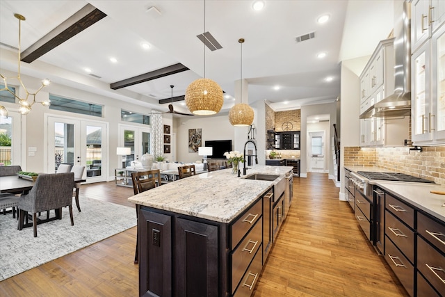 kitchen with high end stove, sink, decorative light fixtures, light hardwood / wood-style floors, and white cabinetry