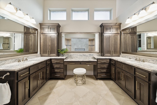 bathroom with a wealth of natural light, a towering ceiling, and vanity