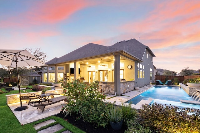 back of property with a patio area, a fenced in pool, and exterior bar