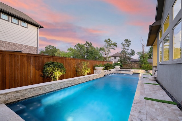 pool at dusk featuring pool water feature