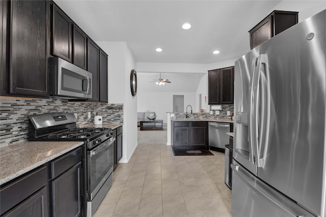 kitchen featuring backsplash, dark brown cabinetry, stainless steel appliances, vaulted ceiling, and ceiling fan